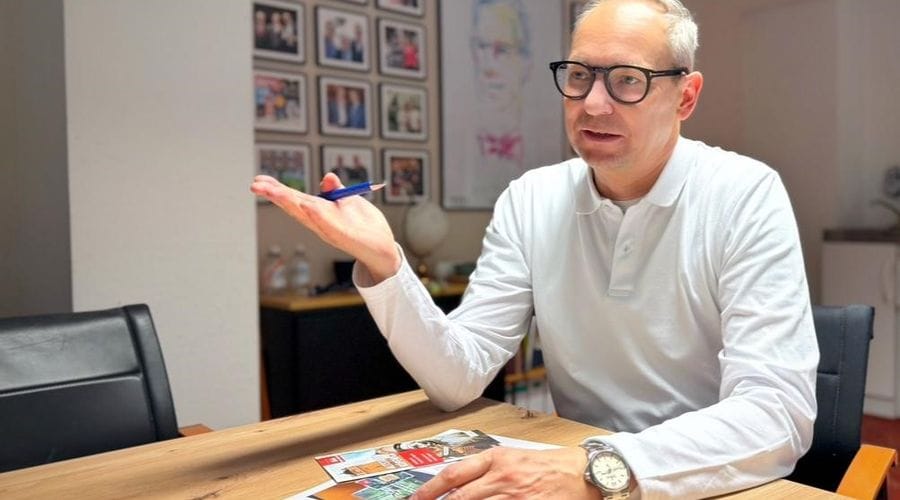 Mathis Richter, Geschäftsführer des Tourismusvereins Berlin Treptow-Köpenick e.V., sitzt an einem Konferenztisch in seinem Büro und gestikuliert während eines Gesprächs. Vor ihm auf dem Tisch liegen touristische Informationsmaterialien, im Hintergrund sind gerahmte Fotos an der Wand zu sehen.